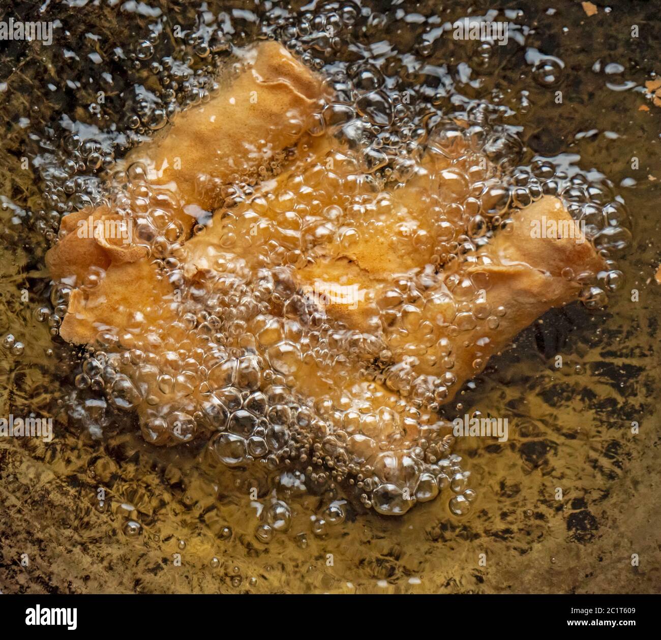 Close up shot of deep fried spring rolls being fried in hot oil in a