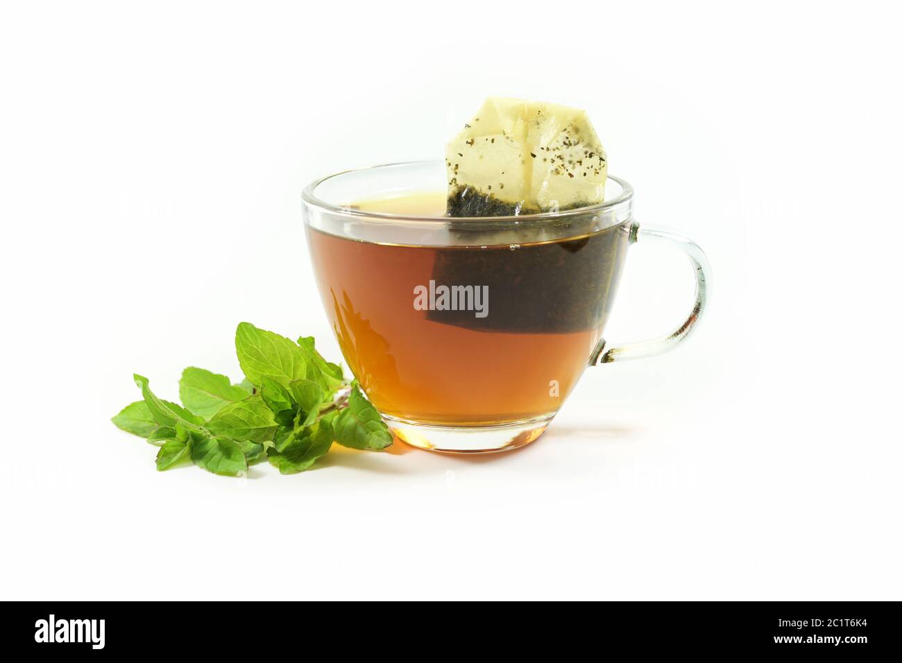 Healthy hot drink, herbal tea bag in a glass cup and a few fresh peppermint leaves isolated on a white background, copy space, selected focus Stock Photo