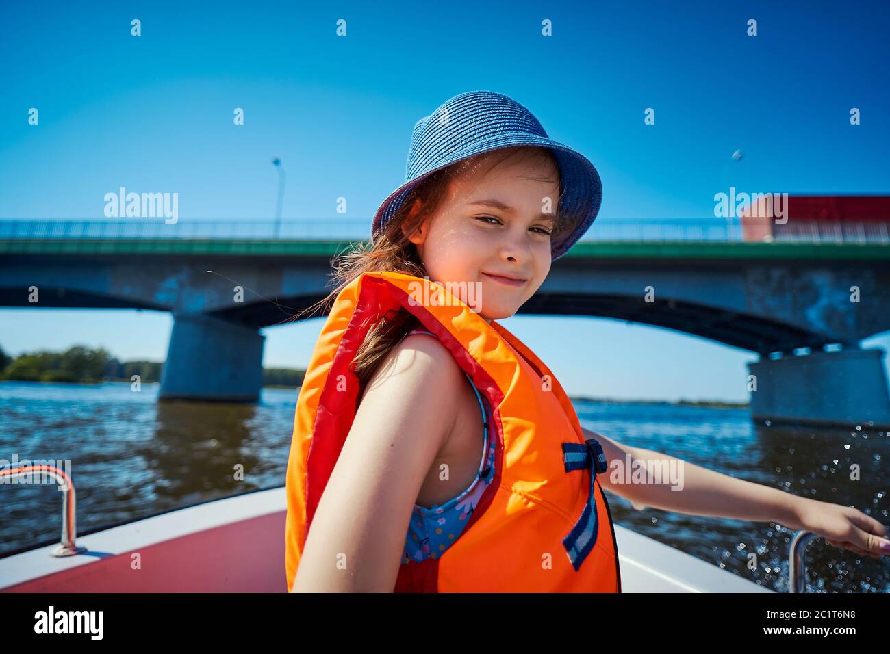 little girl in a swimming vest sits in a motorboat  Stock Photo