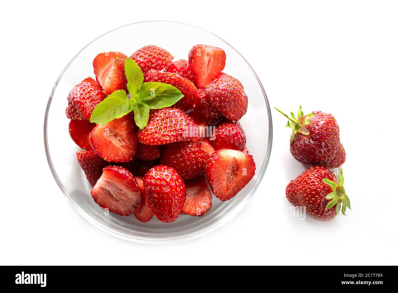 Dessert from fresh strawberries with peppermint garnish in a glass bowl, isolated with shadows on a white background, high angle view from above Stock Photo