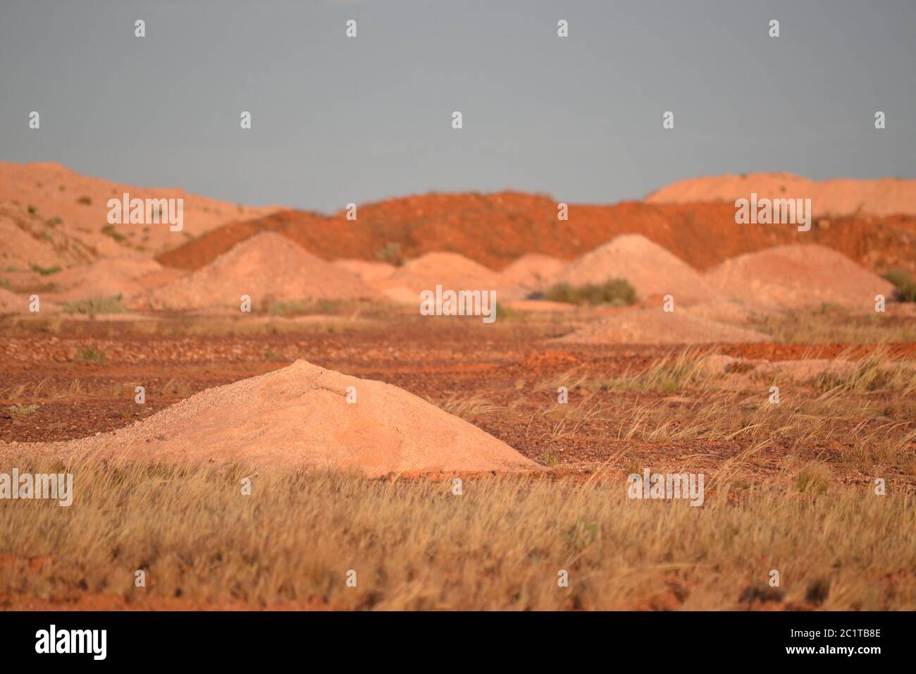 Desolate landscape of mine tailing mounds of rock and red dirt near the outback opal mining town of Coober Pedy in Australia Stock Photo