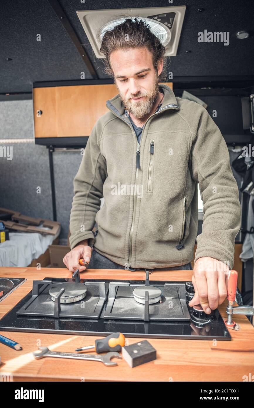 Man testing new gas stove inside his camper van Stock Photo Alamy