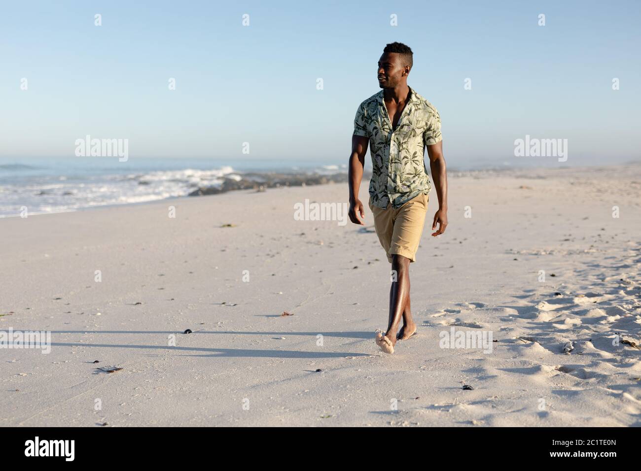 An African American man walking on beach on a sunny day Stock Photo