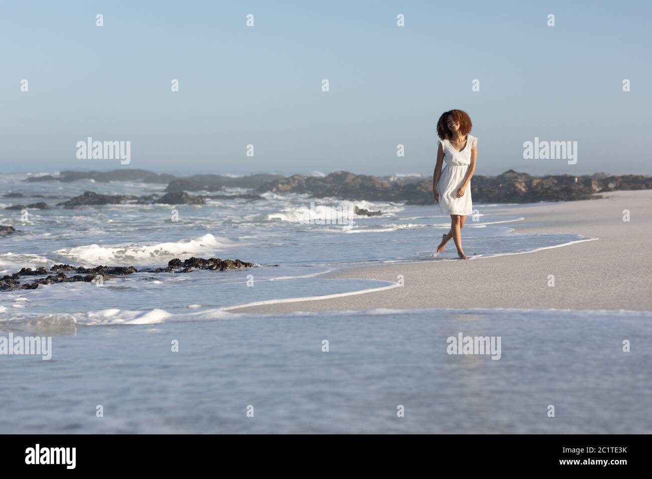 Mixed race woman walking on beach on a sunny day Stock Photo