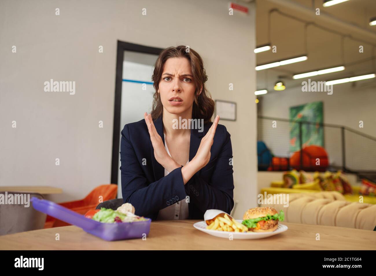Frowning young woman sitting at table before eating Stock Photo