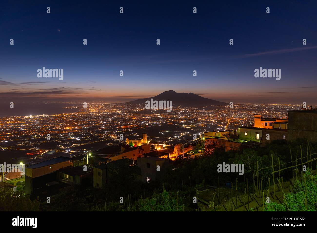 Lettere, Italy. May 12th, 2020. Panoramic view of Mount Vesuvius seen from the village of Lettere after sunset with night lights. Stock Photo
