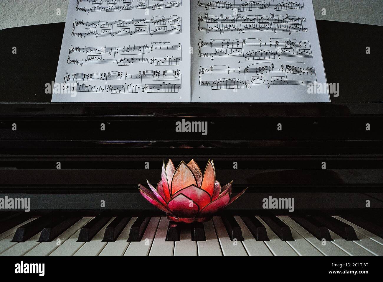 Piano with a candle standing in front of music Stock Photo