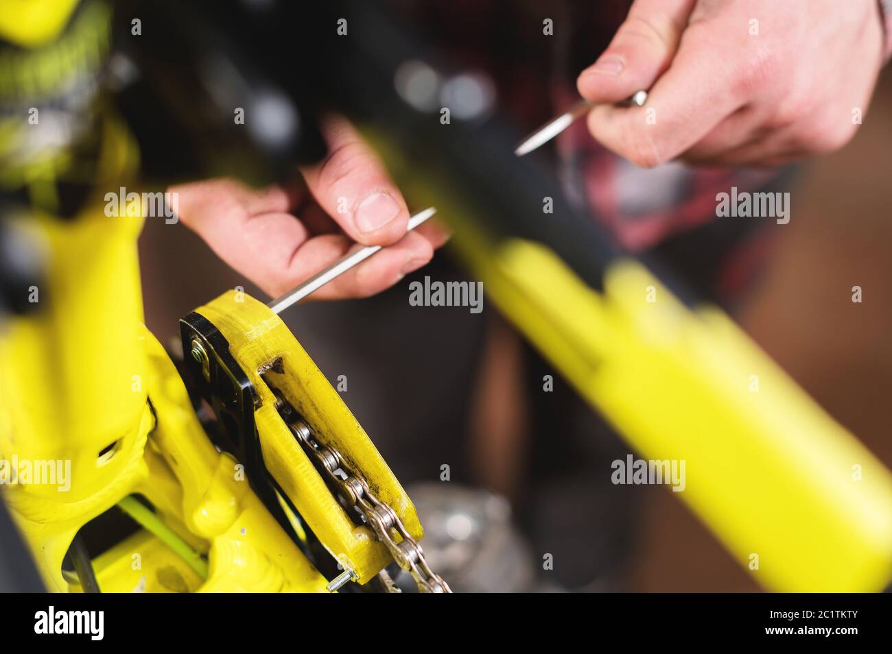 Close-up maintenance of a mountain bike. Male hands adjust the chain tension. Technical condition monitoring in the workshop Stock Photo