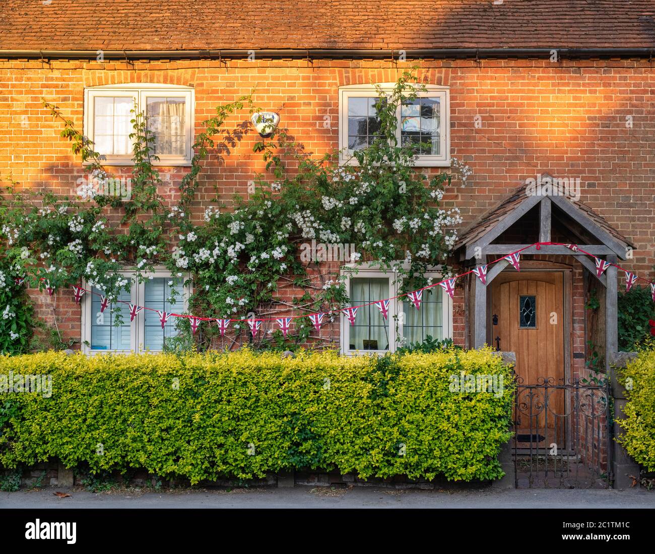 Early morning sunlight, flowers and bunting on a cottage in Stewkley, Buckinghamshire, England Stock Photo
