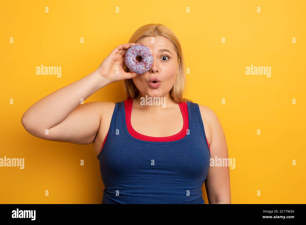 Fat girl eats sweet instead of do gym. Cyan background Stock Photo