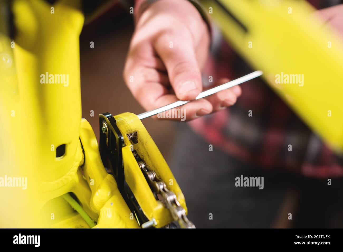 Close-up maintenance of a mountain bike. Male hands adjust the chain tension. Technical condition monitoring in the workshop Stock Photo