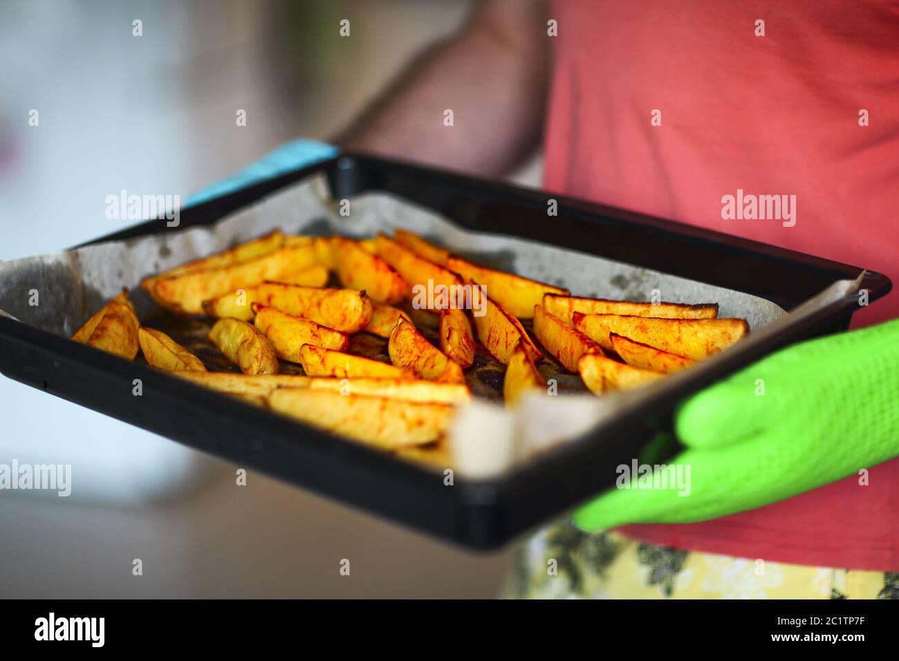Close up shot of roast potatoes and parsnips in a tray. A man is holding it in his hands Stock Photo