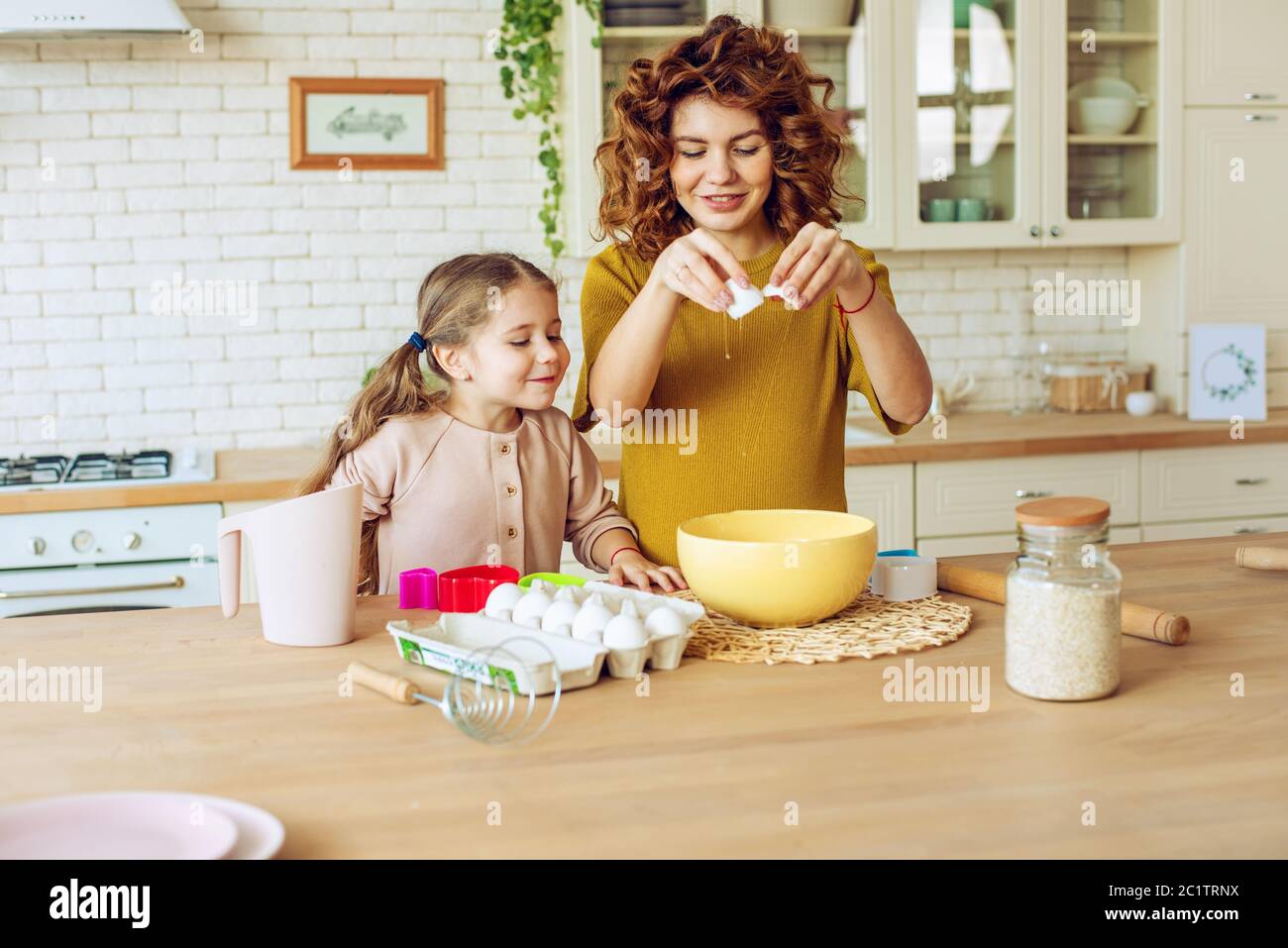 Mother and daughter prepare a cake together in the kitchen Stock Photo