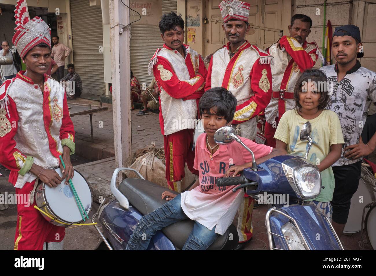 Uniformed Indian wedding band and festival musicians during a break mingling with locals; Mumbai, India Stock Photo