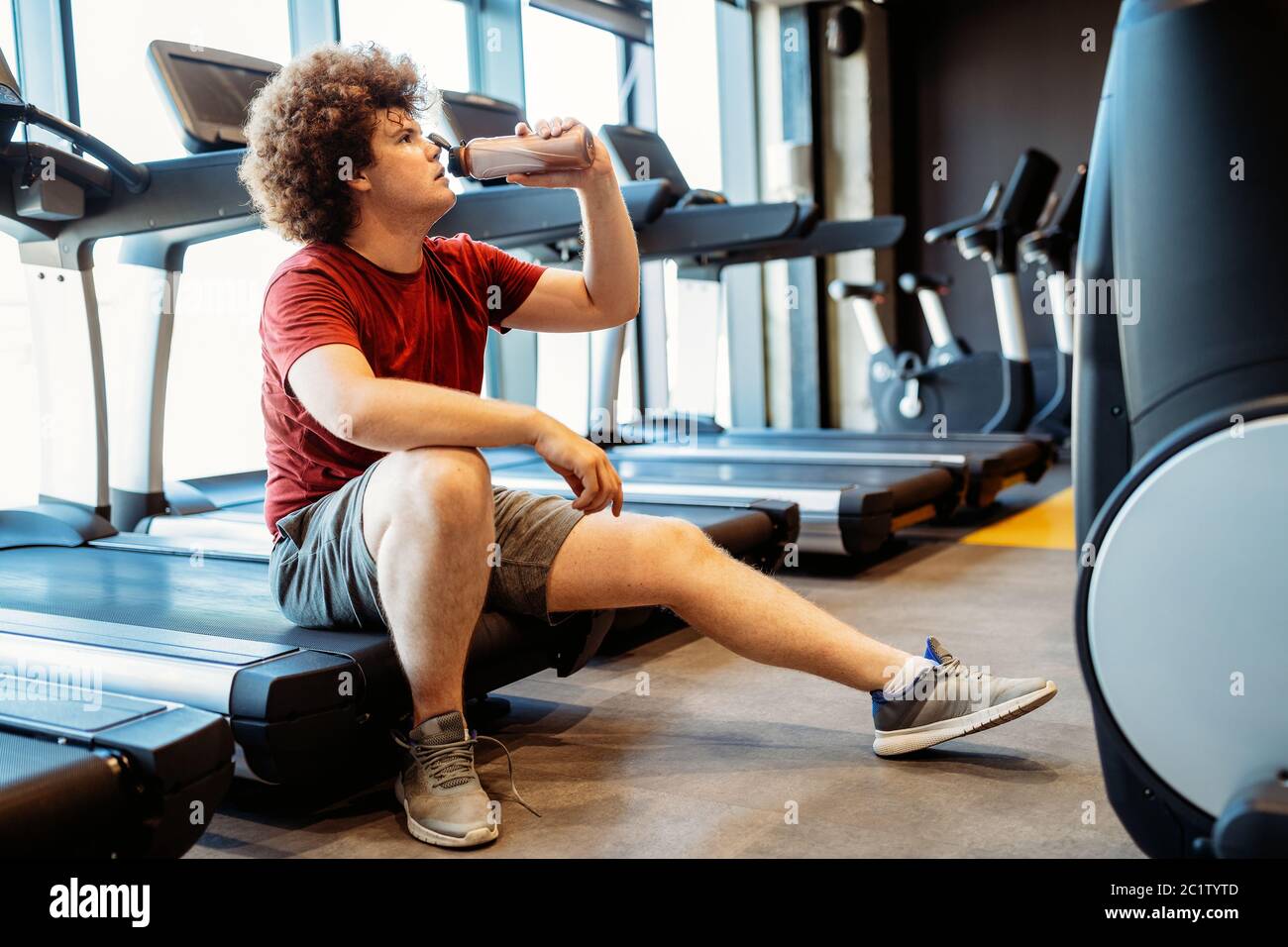 Overweight young man exercising in gym to achieve goals Stock Photo