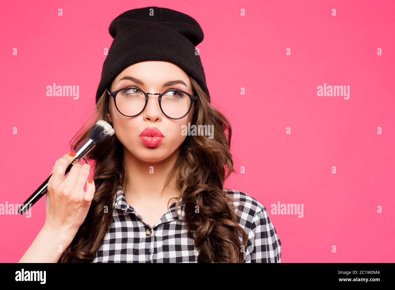 Young hipster girl having fun and going crazy, wearing glasses hat  bright make up. Pink urban background. The woman made his li Stock Photo