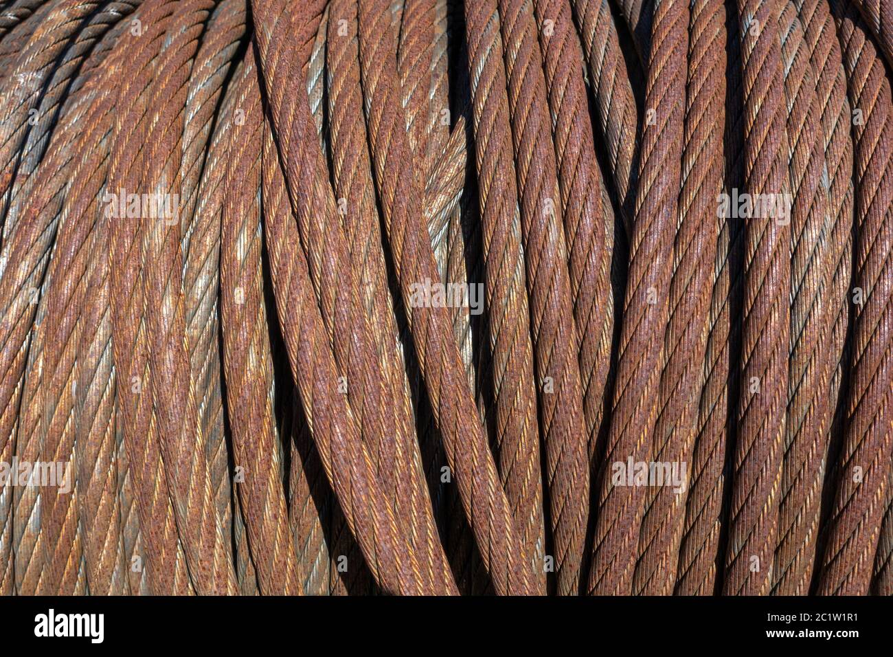 Rusty, thick, coiled wire rope in closeup in the sunshine Stock Photo