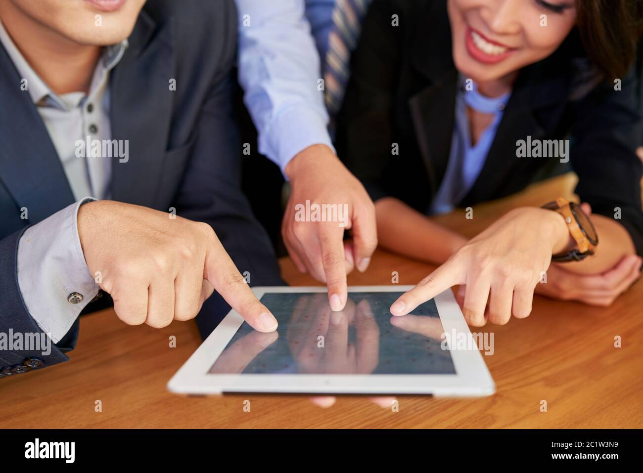 Group of three business people working together using tablet computer ...