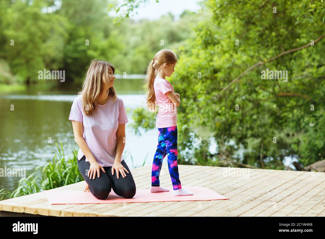 Mom and daughter on morning exercises in the park. The concept of reluctance to train Stock Photo