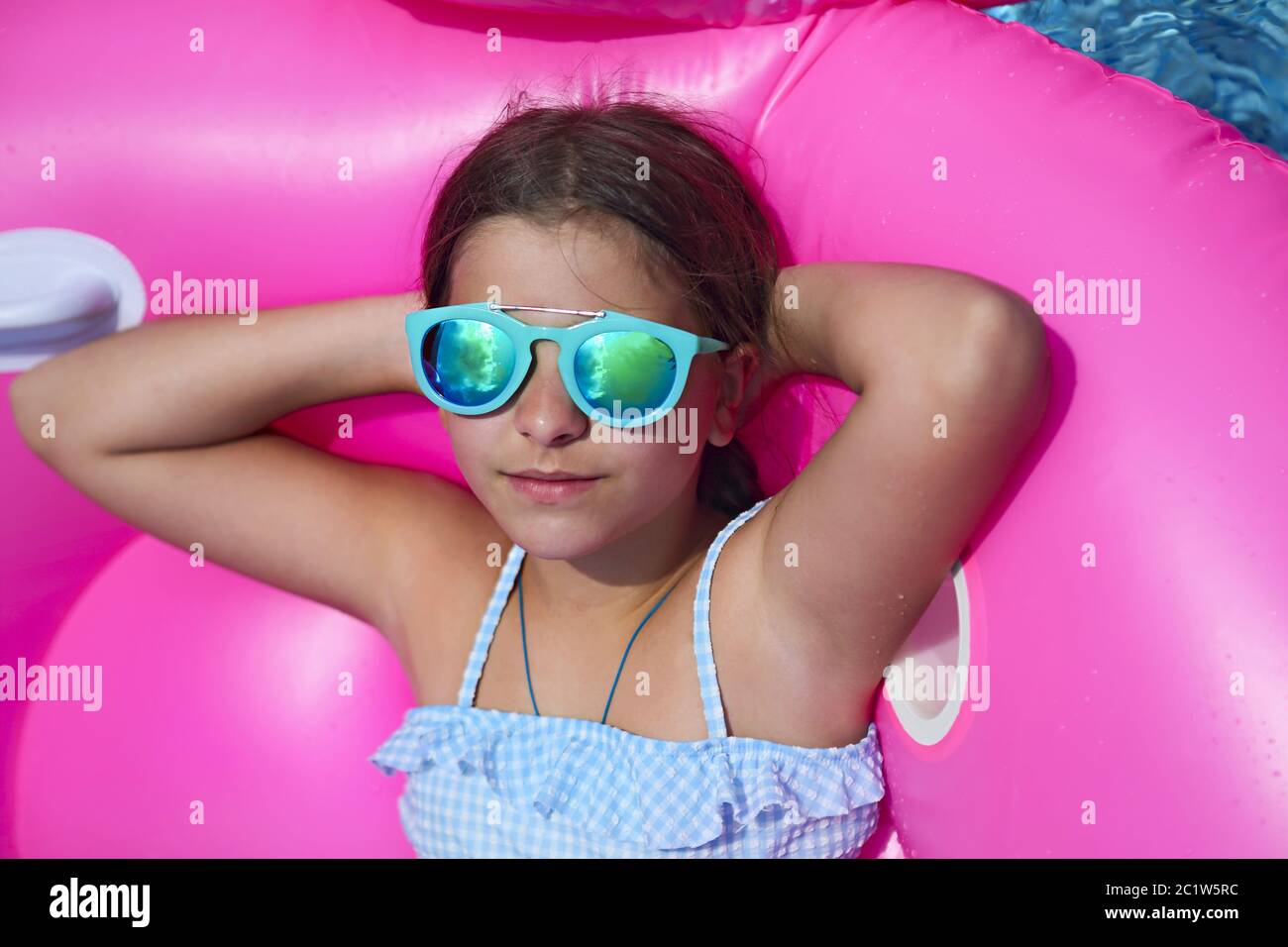 Portrait of little girl wearing sunglasses on inflatable flamingo swim  float Stock Photo - Alamy