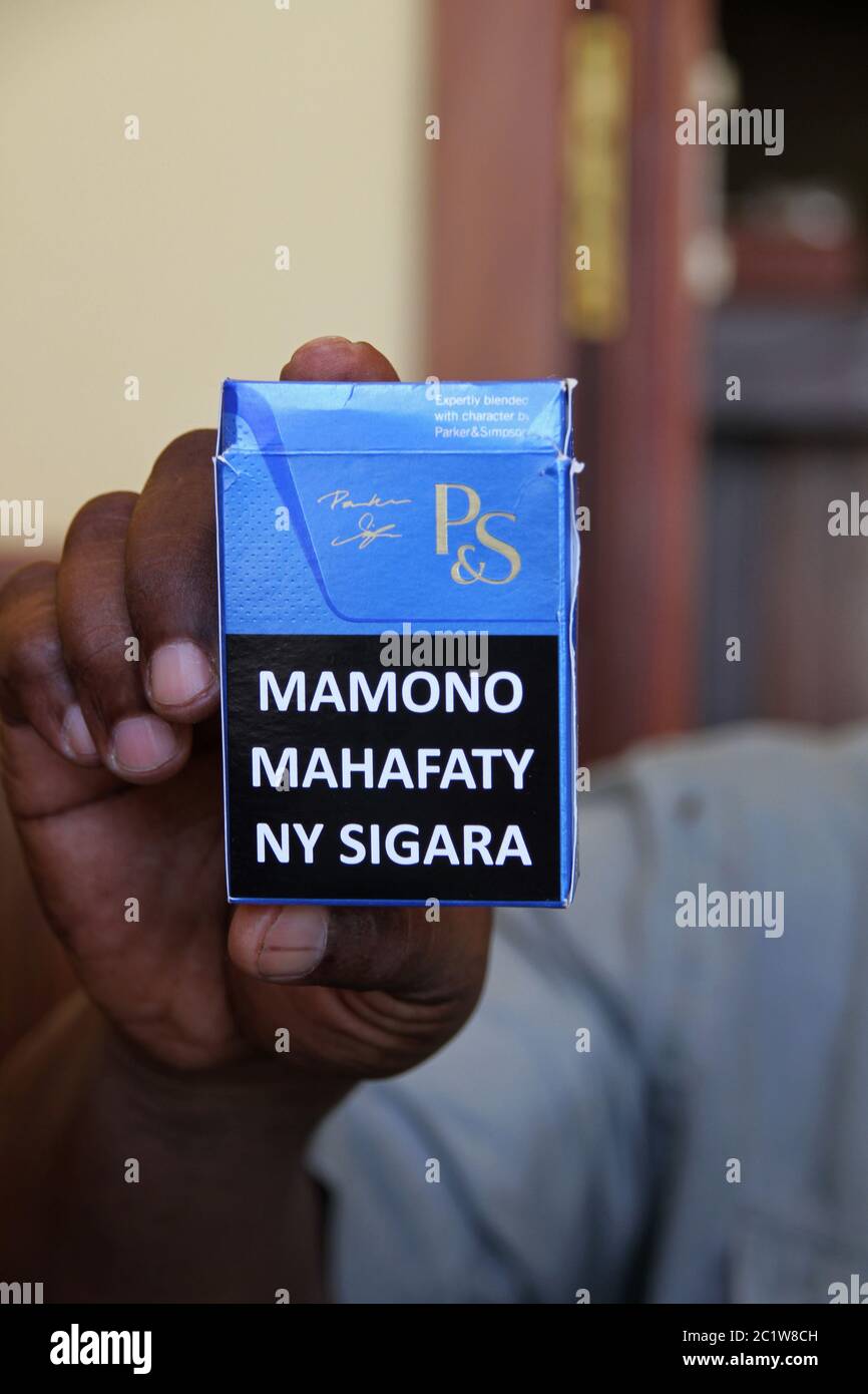 Hand holding Parker & Simpson cigarette packet with warning label picture, Andoany/Hell-Ville City, Nosy Be, Madagascar. Stock Photo