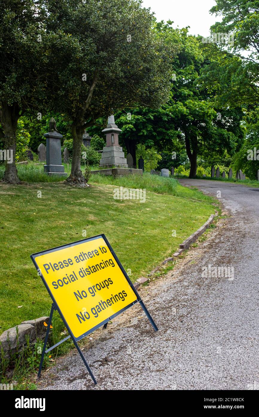 Sign in a graveyard saying ''Please adhere to social distancing, no groups, no gatherings' Stock Photo