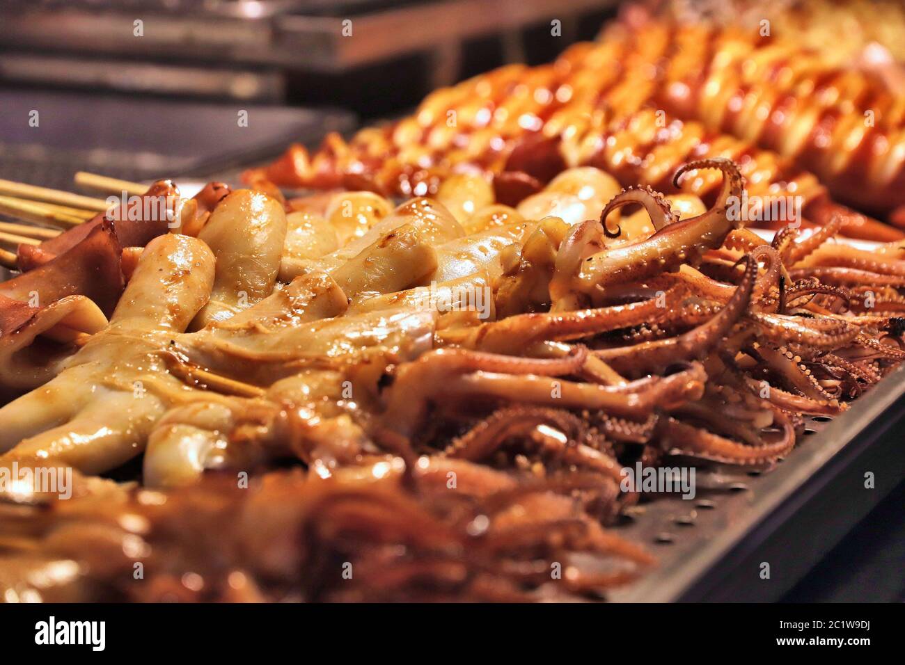 Taiwan night food market - Raohe Night Market in Taipei. Grilled squid and octopus on stick. Stock Photo