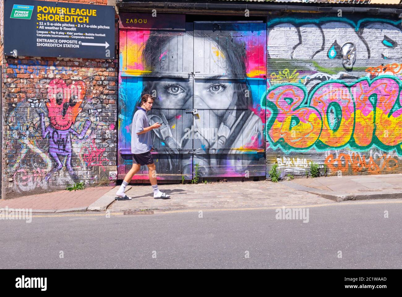 A man walking down Brick lane past Street Art Stock Photo - Alamy