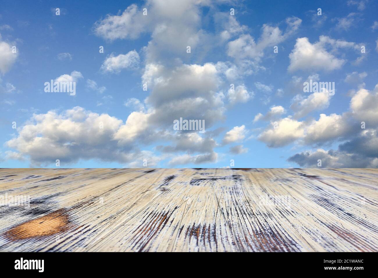 old painted washed oak wooden table on the blue sky clouds background