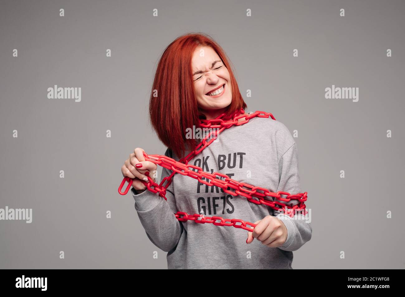 girl entangled in a chain,A red-haired woman with brown hair tries to get rid of the chain Stock Photo
