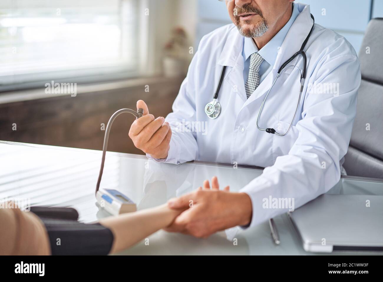 Young woman at the doctor appointment. The doctor measures the pressure of the patient Stock Photo