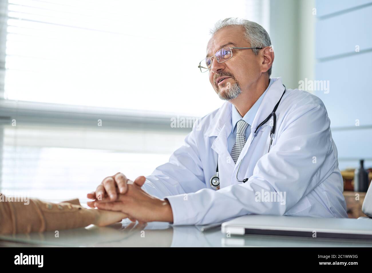 Doctor and patient are discussing something, just hands at the table Stock Photo