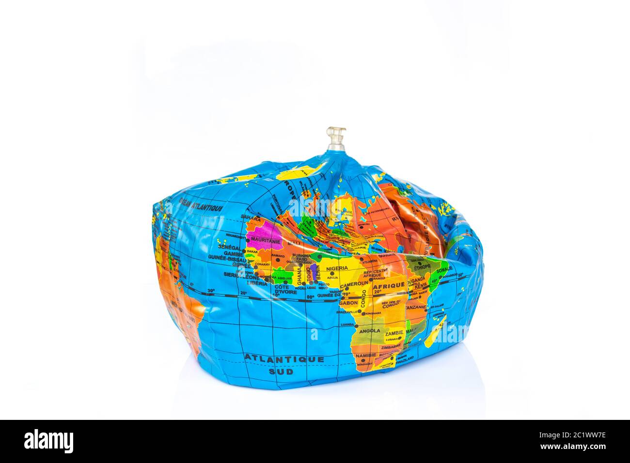 Planet earth toy balloon deflated isolated on white background. Earth overshoot day, unsustainable resources consumption concept Stock Photo