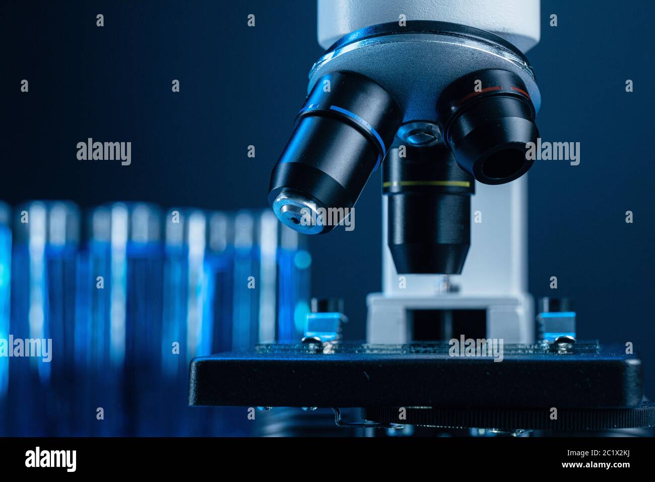 Close up of laboratory microscope with set of test tubes with blue ...