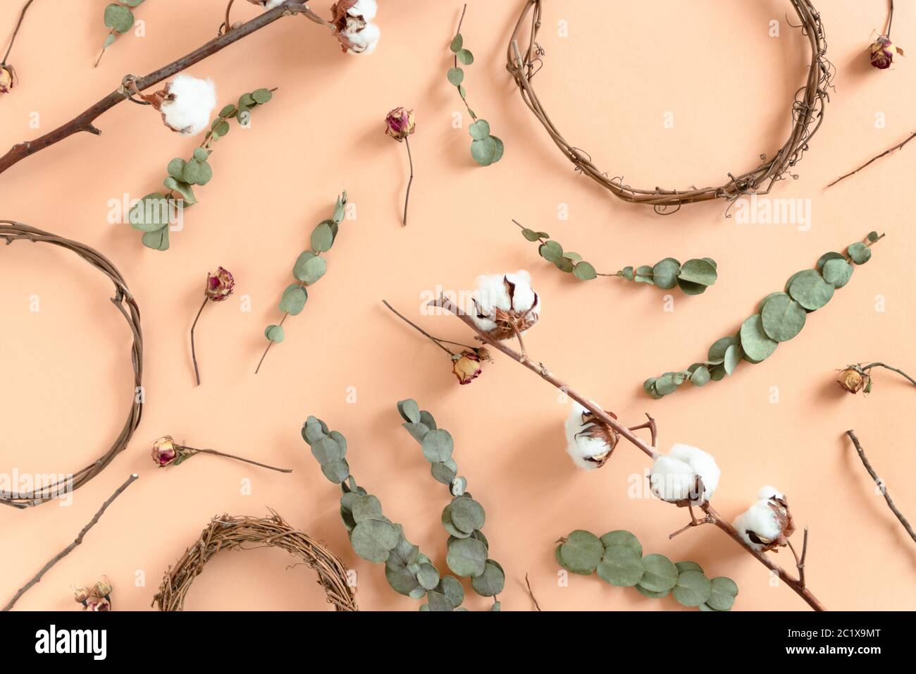 Pattern made of wreath blanks, dried eucalyptus, roses, cotton branches on yellow background Stock Photo