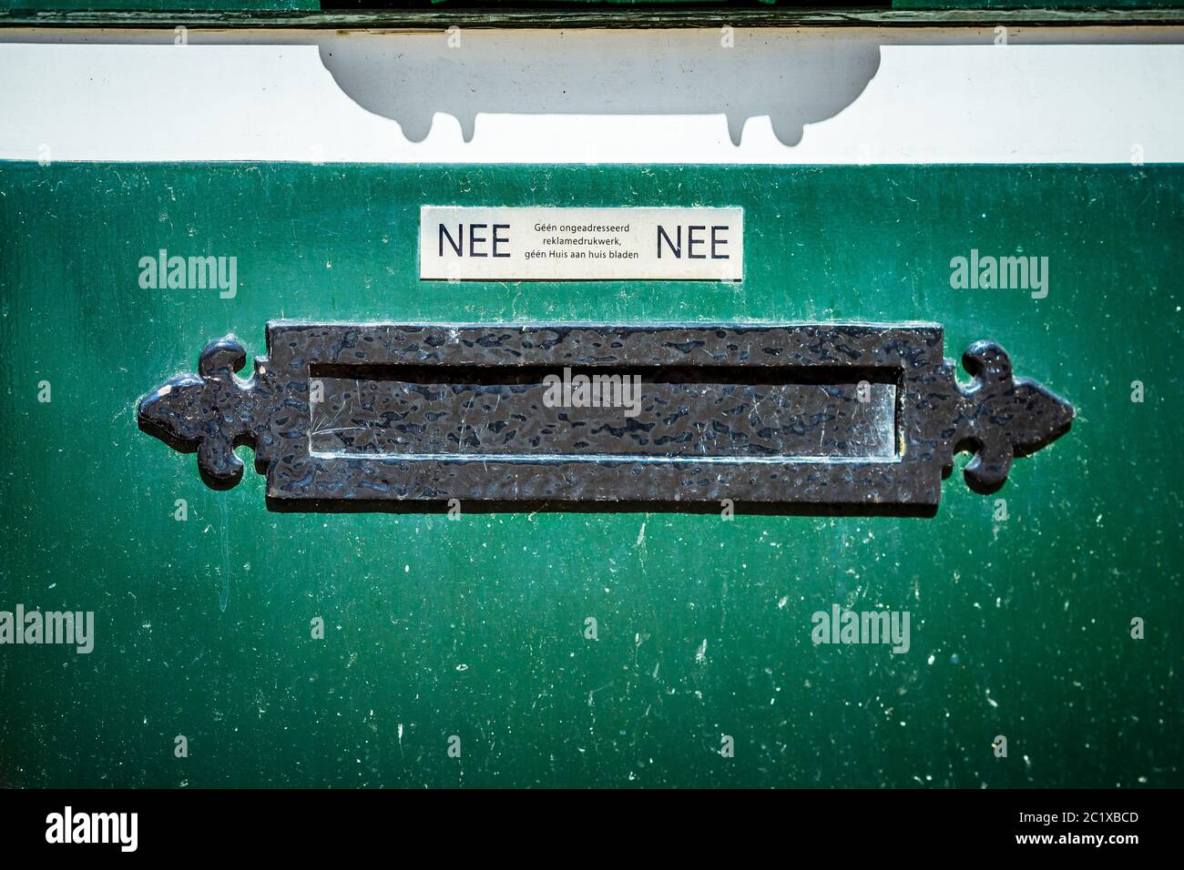 Old horizontal letterbox in a green door, dutch sticker saying no to advertising and leaflets Stock Photo