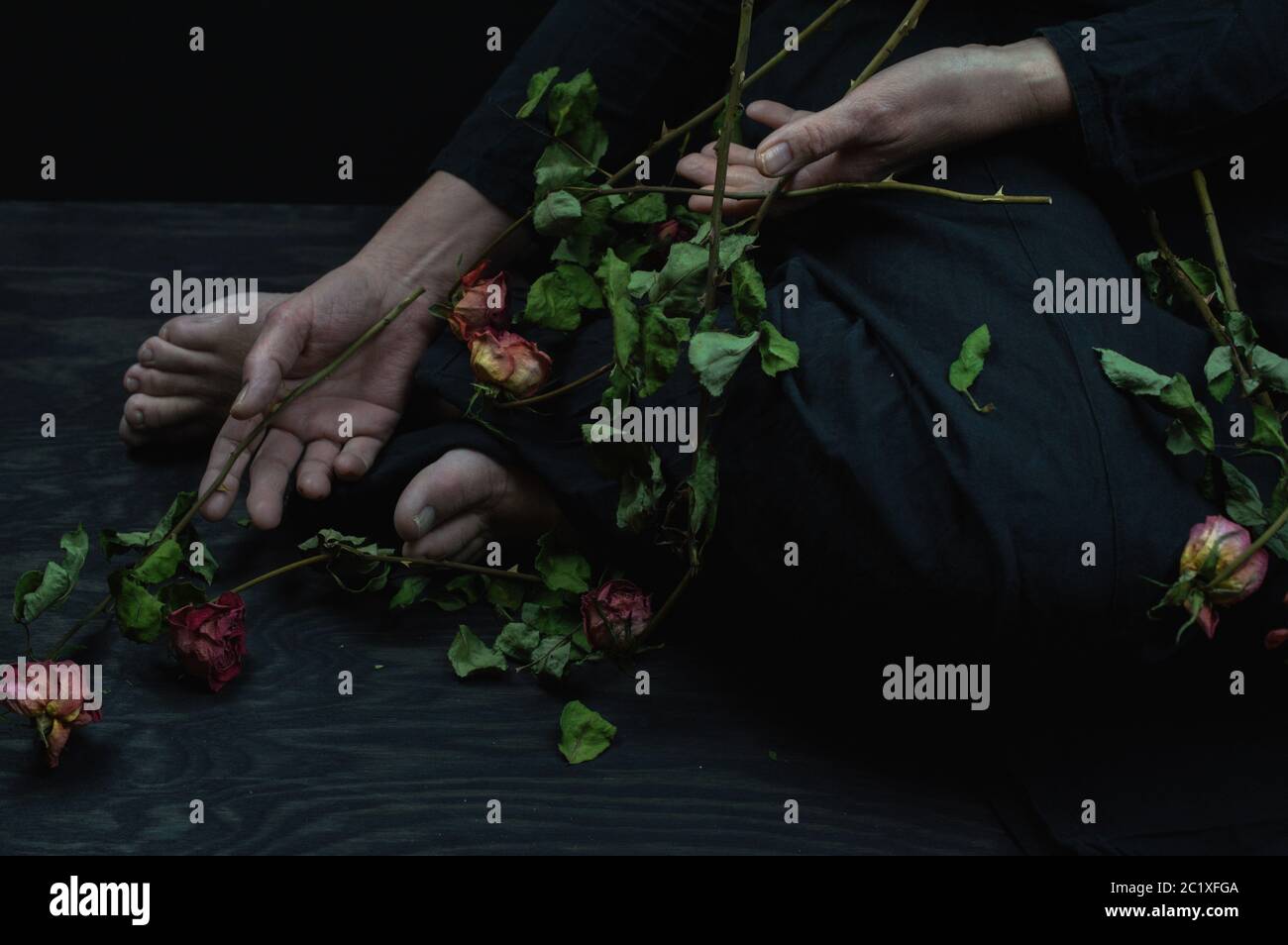 a woman holding a bouquet of dead roses Stock Photo