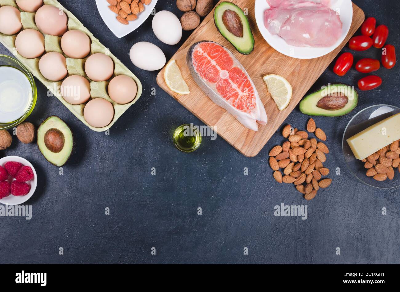 Keto diet, low carb healthy food. avocado, fish, oil, nuts on black background Stock Photo