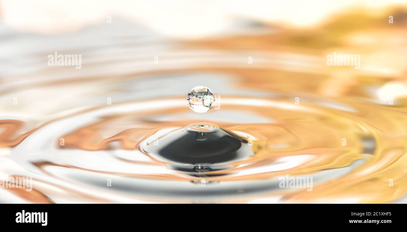 a drop of water dripping into the water on the background of autumn leaves, close-up Stock Photo