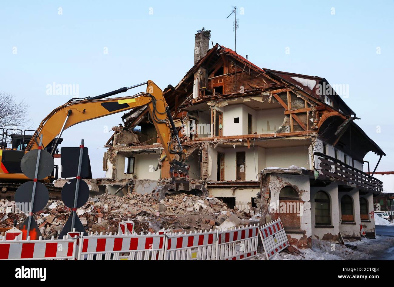An old dilapidated house is torn down with an excavator Stock Photo