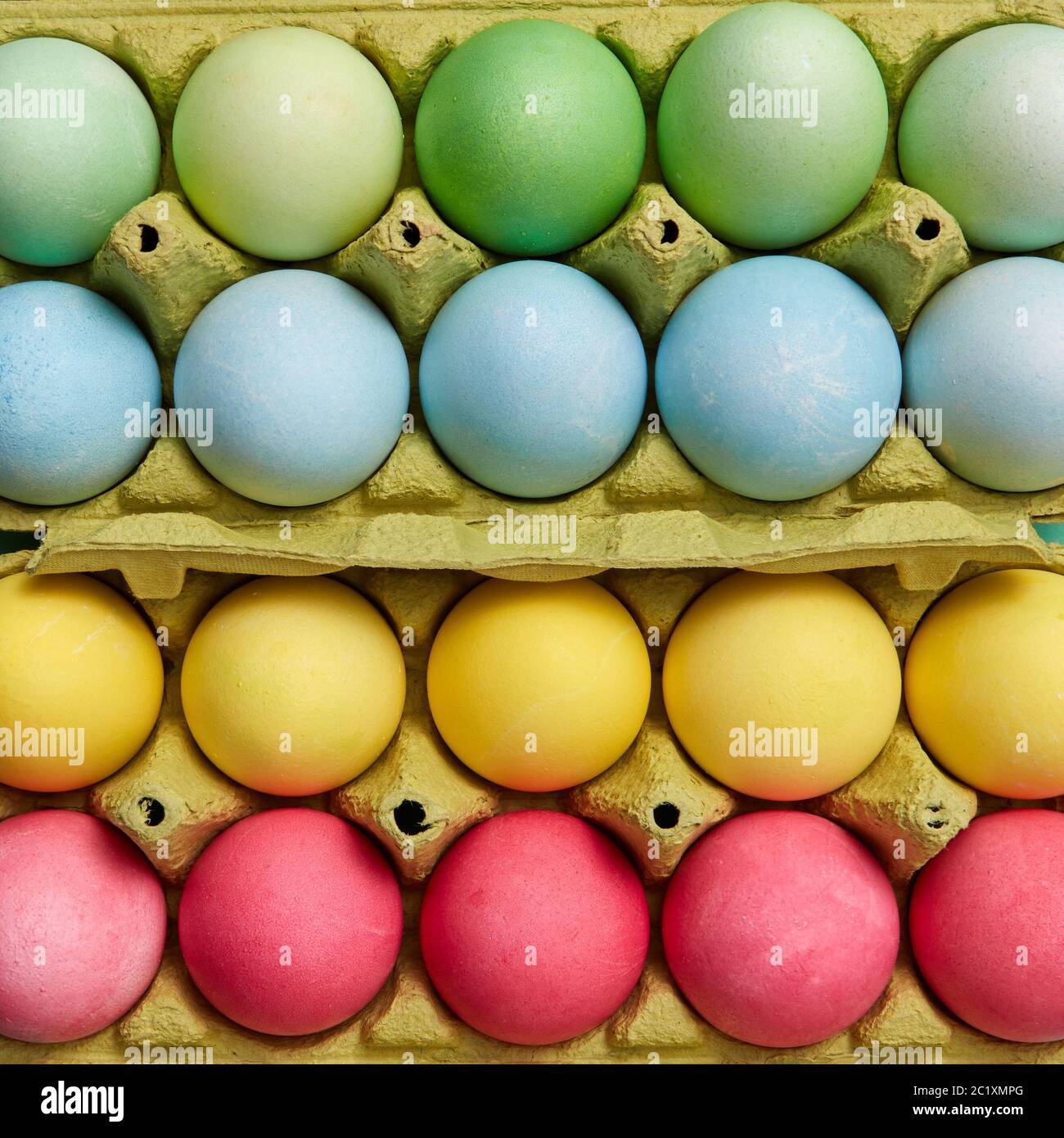Different colored painted Easter eggs in yellow cardboard boxes. Creative Easter pattern as layout. Flat lay Stock Photo
