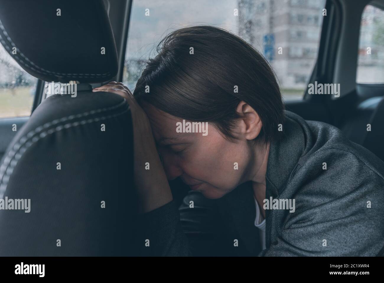 Tired businesswoman sleeping at car back seat, exhausted female executive fallen asleep in corporate limousine Stock Photo