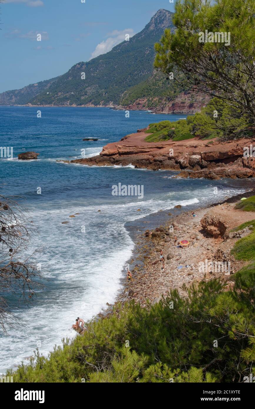 Es Corrals Fais, a remote pebbly beach with a few people relaxing on it, relaxing on it, near Banyalbufar, Mallorca north coast, August. Stock Photo