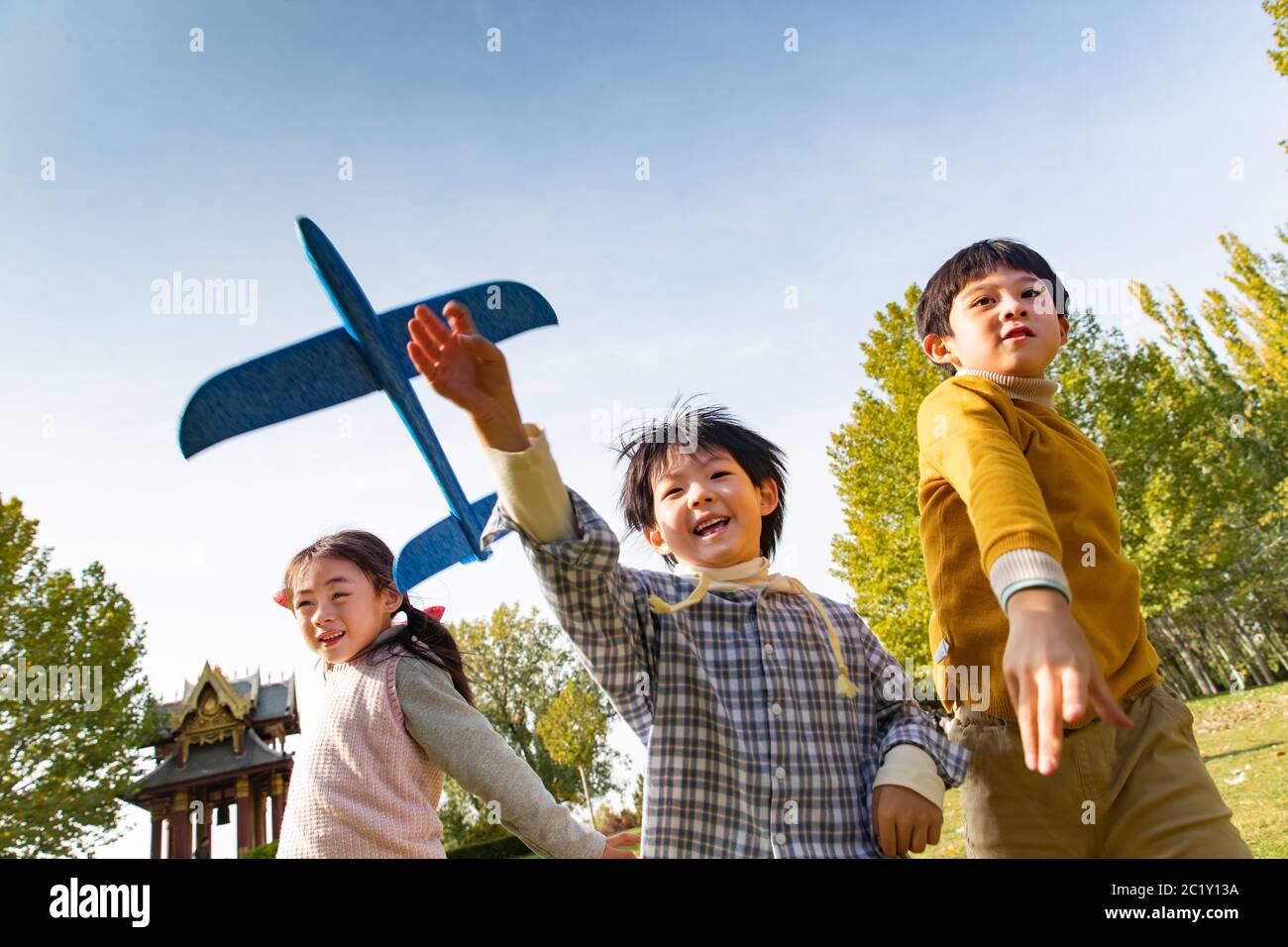 Happy children playing in the park with a toy plane Stock Photo