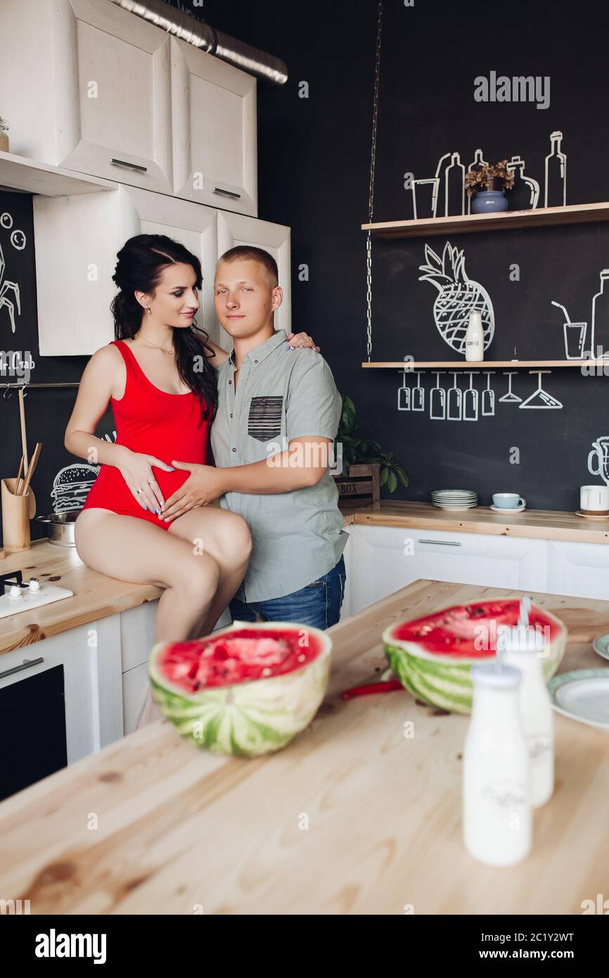 Caring husband kissing pregnant wife while cooking dinner Stock Photo