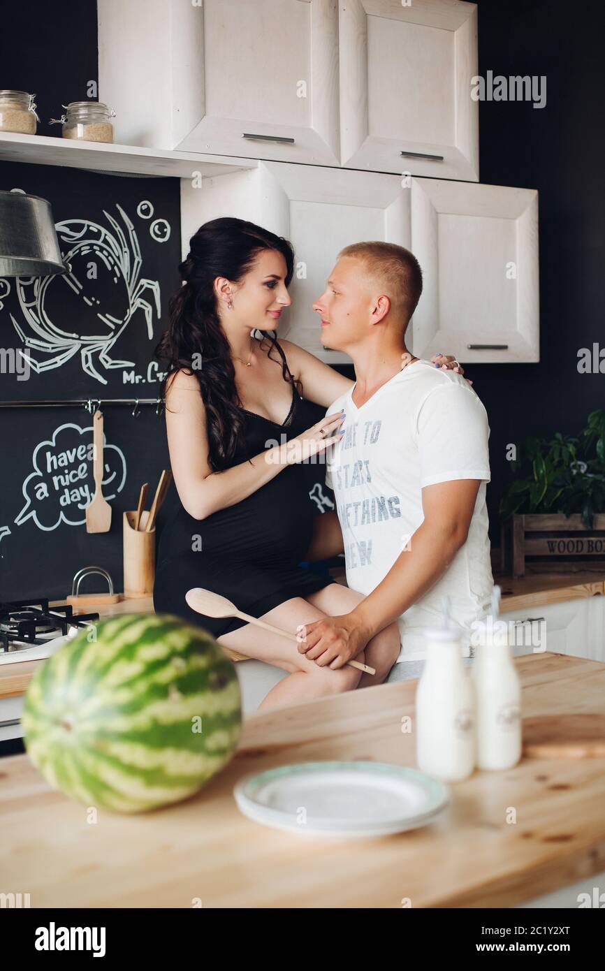 View from side of cute pair kissing while cooking at kitchen Stock Photo