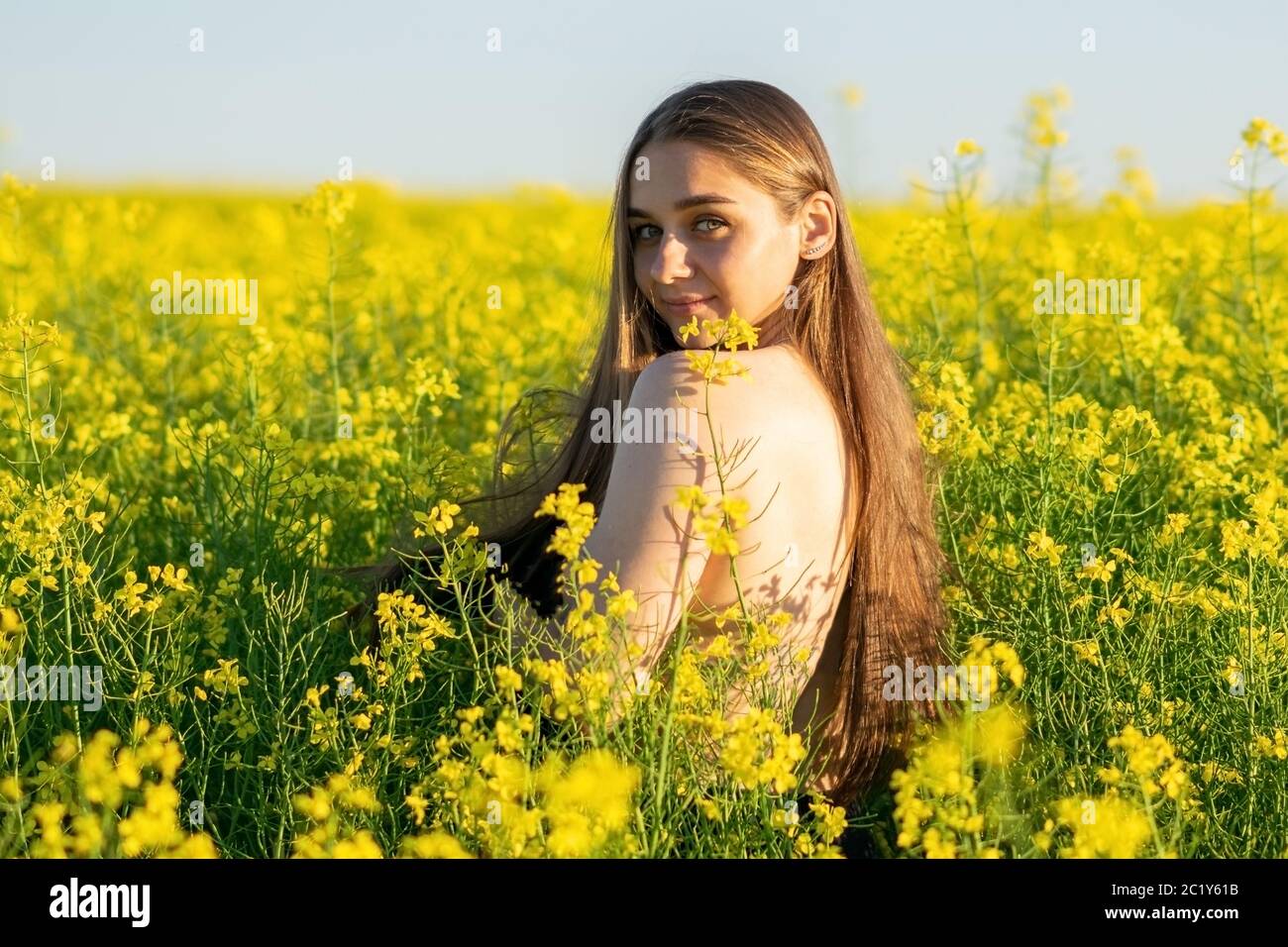 Beautiful girl in a rapeseed field, with an open shoulder. Stock Photo
