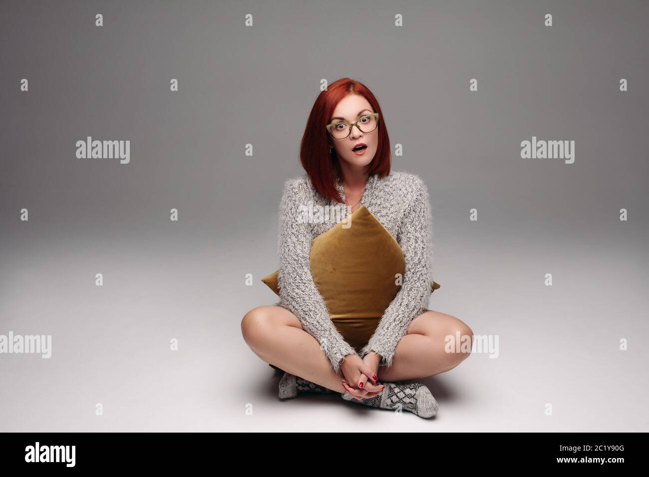 Red Haired Girl In Grey Sweater And Warm Socks Sitting On Floor In