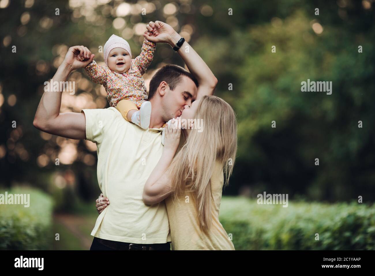 Portrait of lovely young family sitting together outside. Stock Photo