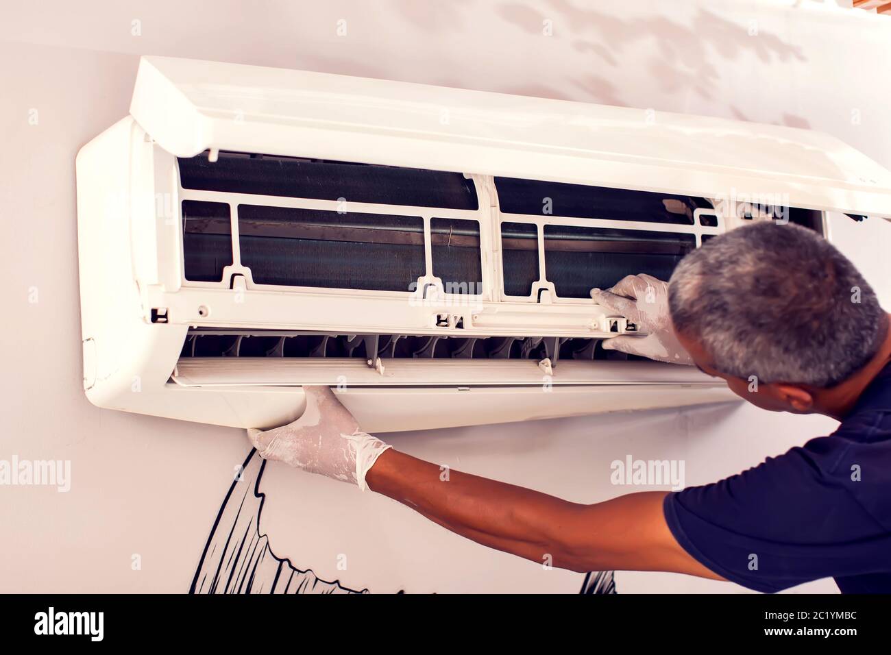 Man worker fixing air conditioning on the wall. Professional service Stock Photo
